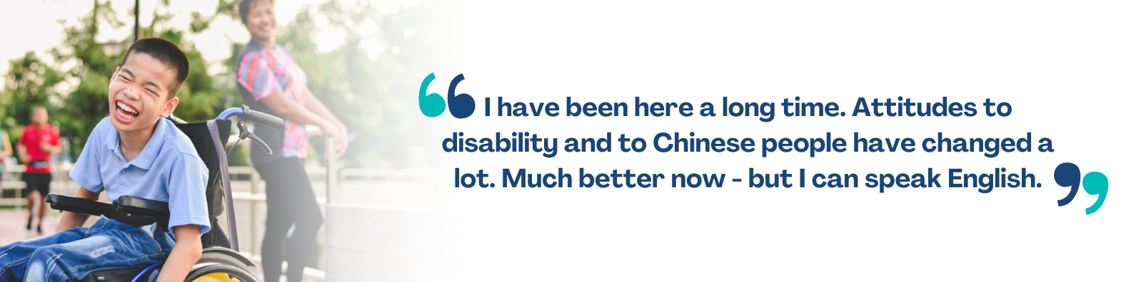 An image of a young Chinese Australian boy in a wheelchair laughing, with his carer behind him.