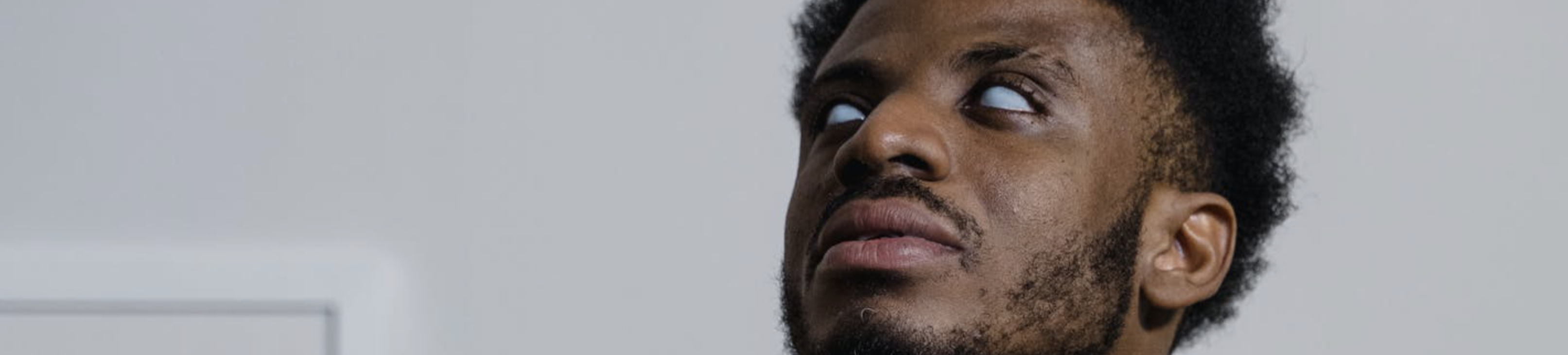 A blind man with dark skin looks upwards