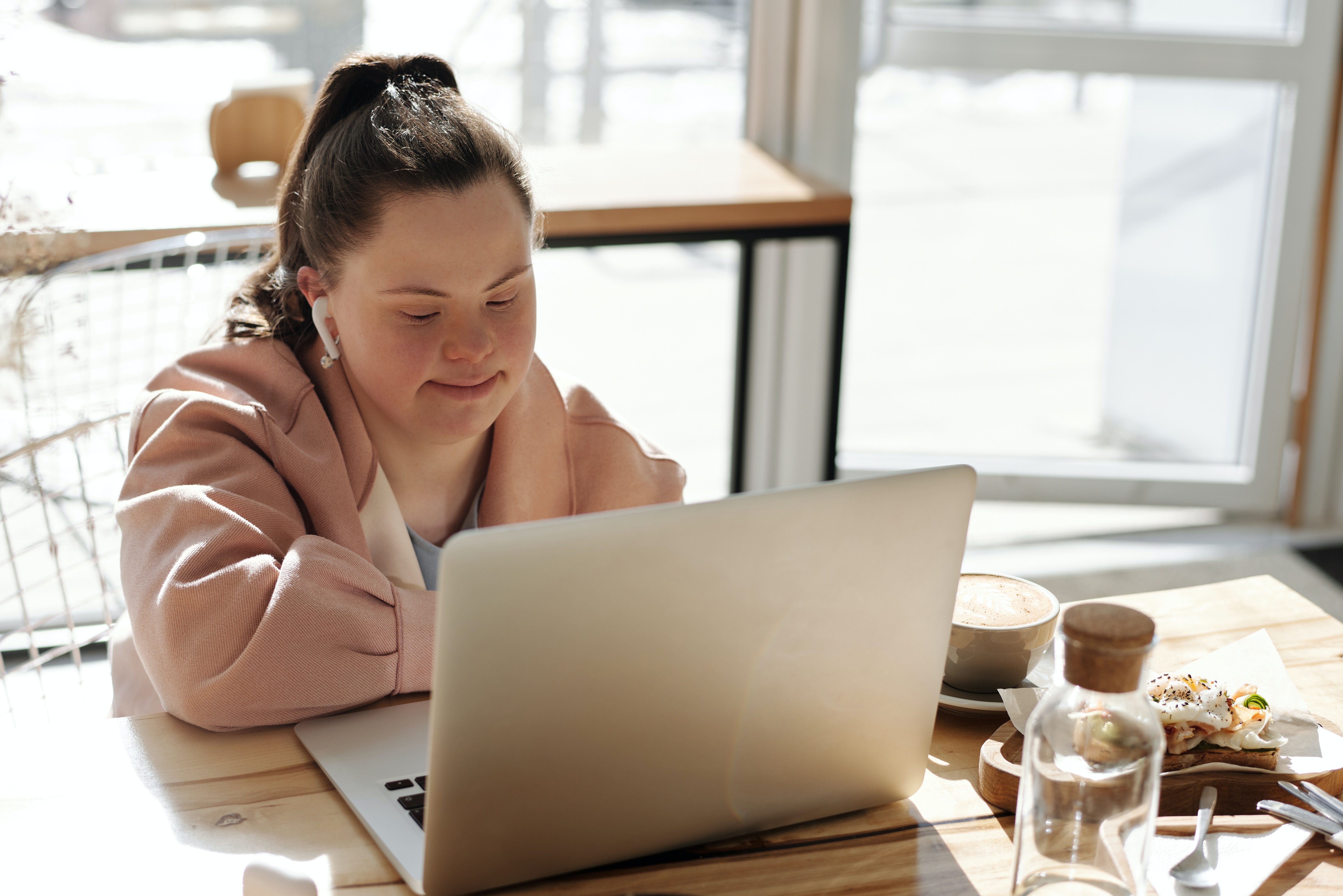A woman with Down syndrome wears earphones as she sits at the computer